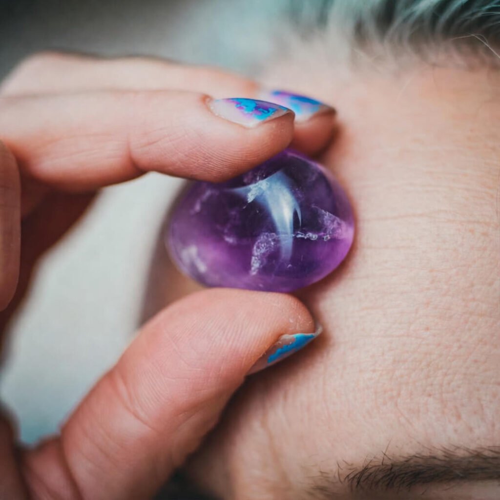 Chipped nail hand placing amethyst on third-eye