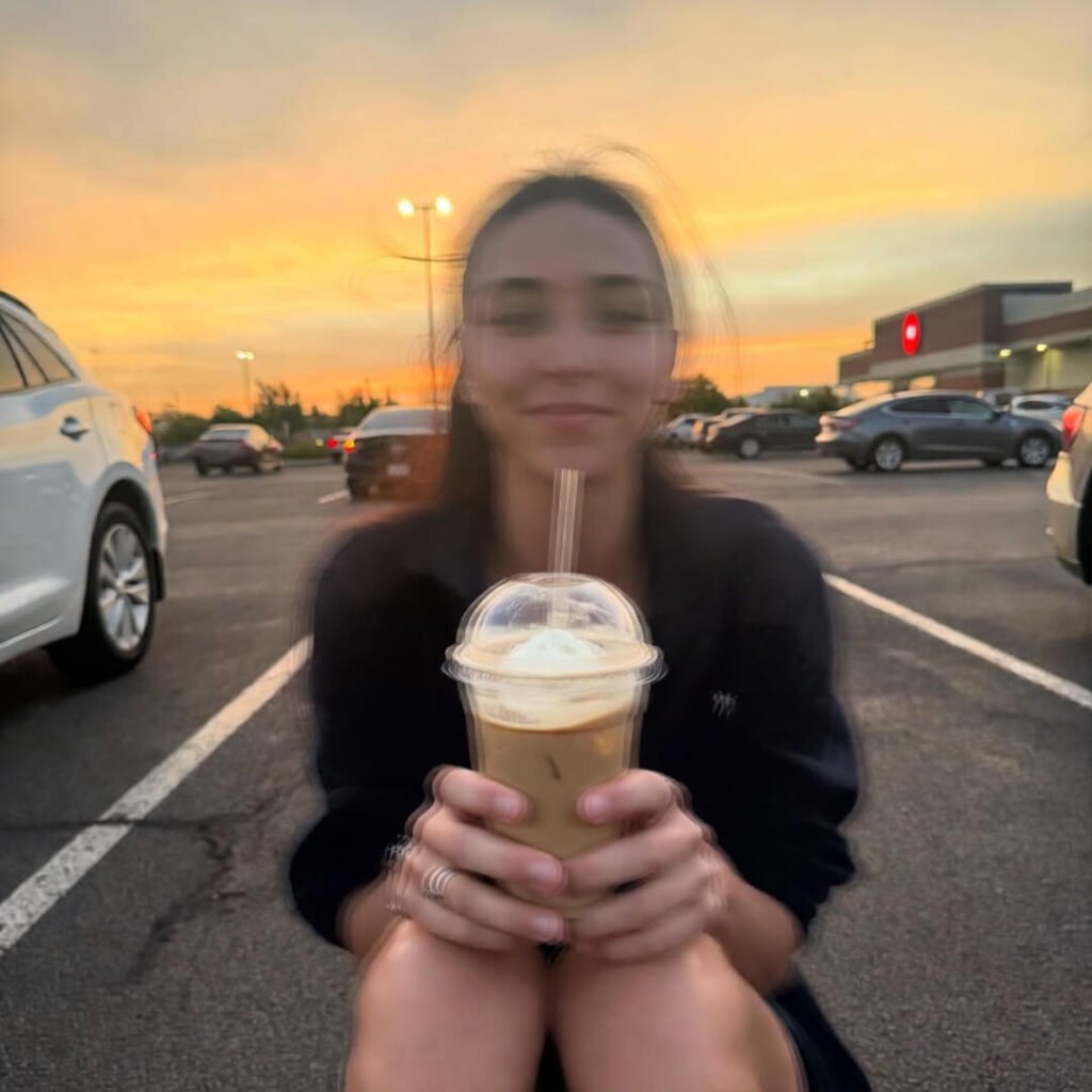 Person sitting on Target parking lot curb at sunset, reverently holding melting iced coffee.